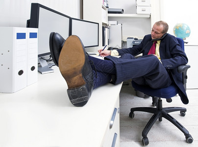 脚Y子鞋服用商人在电话上作笔记脚舒服地坐在桌上的子坐着背景