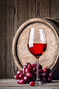 饮料材液体红酒杯和葡萄子其背景是木桶底面的葡萄红酒杯加图片