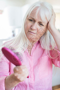 担心的负责理发年长妇女对头发损失的关注刷陈年图片