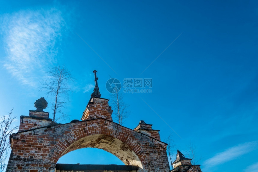 红砖的旧教堂大拱门在俄罗斯一片蓝天背景上长得过于茂密废墟建筑学结石图片