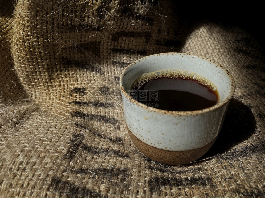 陶瓷制品传统杯中的热咖啡在古典豆沙袋上优质的传统图片