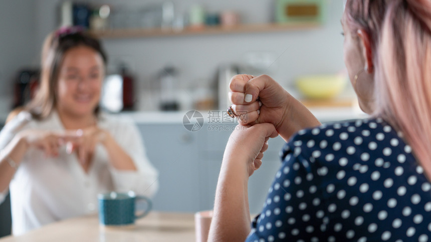 快乐的两名妇女在家中使用手语交谈水平的言图片