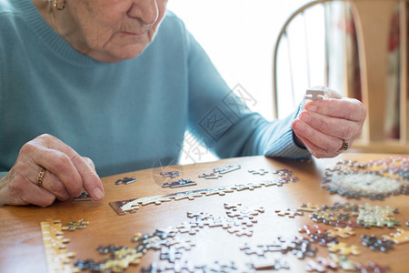 智力女近距离的年长妇女在家里用拼锯猜谜来放松人们图片