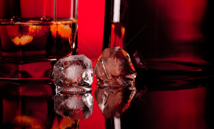 威士忌酒解冻红色的两块冰方和威士忌放在玻璃桌上图片