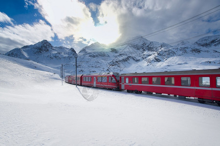 穿过雪火车冬天红色的运输瑞士山火车BerninaExpress穿过高山雪越了伯尔尼纳快车背景