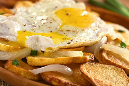 香脆的盘子跑步煎鸡蛋的黄在酥脆炸土豆片上流下用炸洋葱和选择聚焦在流下蛋黄的前面图片