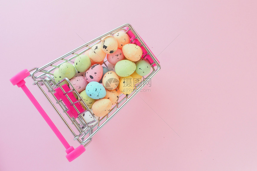 黄色的蓝提供由复活节销售概念上方的粉红背景观点所呈现的一小辆迷你食品车中的多种色微型人工鸡蛋图片