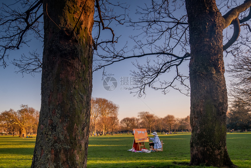 英国伦敦2019年月4日女艺术家坐在木椅子上画在Ravenscout公园的白色坎瓦斯丙烯酸纤维艺术的二月图片