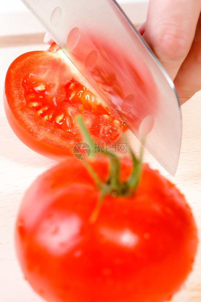 早餐女用刀砍手切新鲜红西番茄有机的厨师图片
