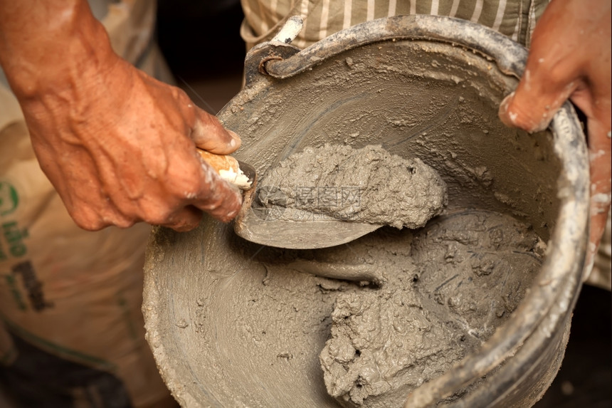 砂浆抹刀工匠水泥迫击与桶中土混在一起图片