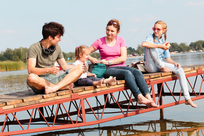 娱乐在夏季阳光明媚的一天家庭起渡假时间在湖边的码头上吃点心零食兄弟孩子们图片