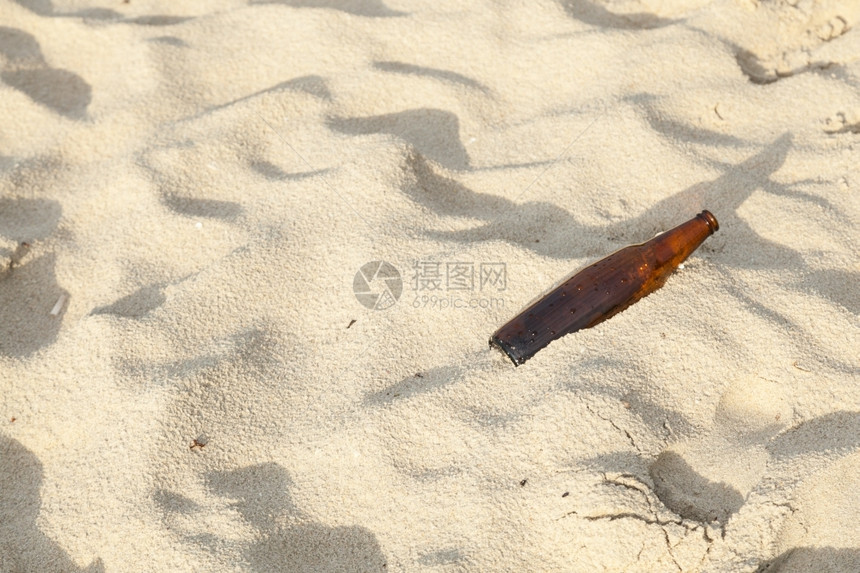 瓶子留在海滩上污染被游客摧毁的垃圾堆积成灰烬在沙滩上丢弃着酒瓶蓝色的喝夏天图片
