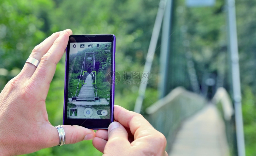 在拍摄自然之桥照片时男手握着机并用亲拍摄一张照片使用手机的近距离观察显示照片infowhatsthis一种保持聪明的图片