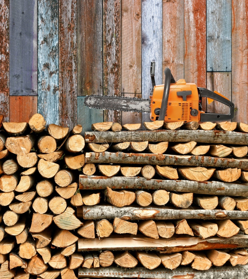 贮存细节桦木堆积的柴和链锯以挡风化的木墙图片