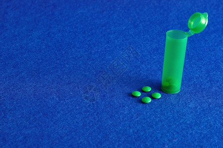 医疗的保护在蓝色背景下被隔离的带有小绿药瓶色丸片胶囊图片