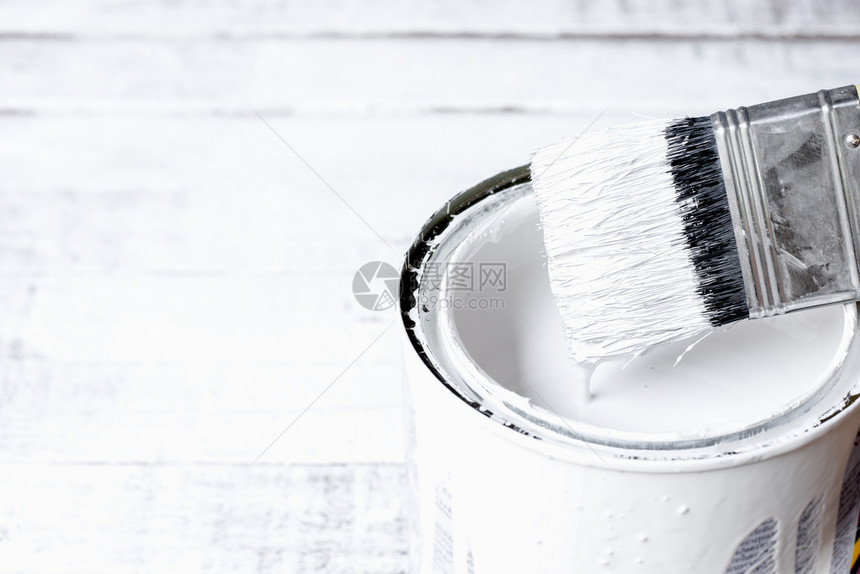 艺术的木头液体油漆刷子被浸在放白木地板上的油漆罐头中图片