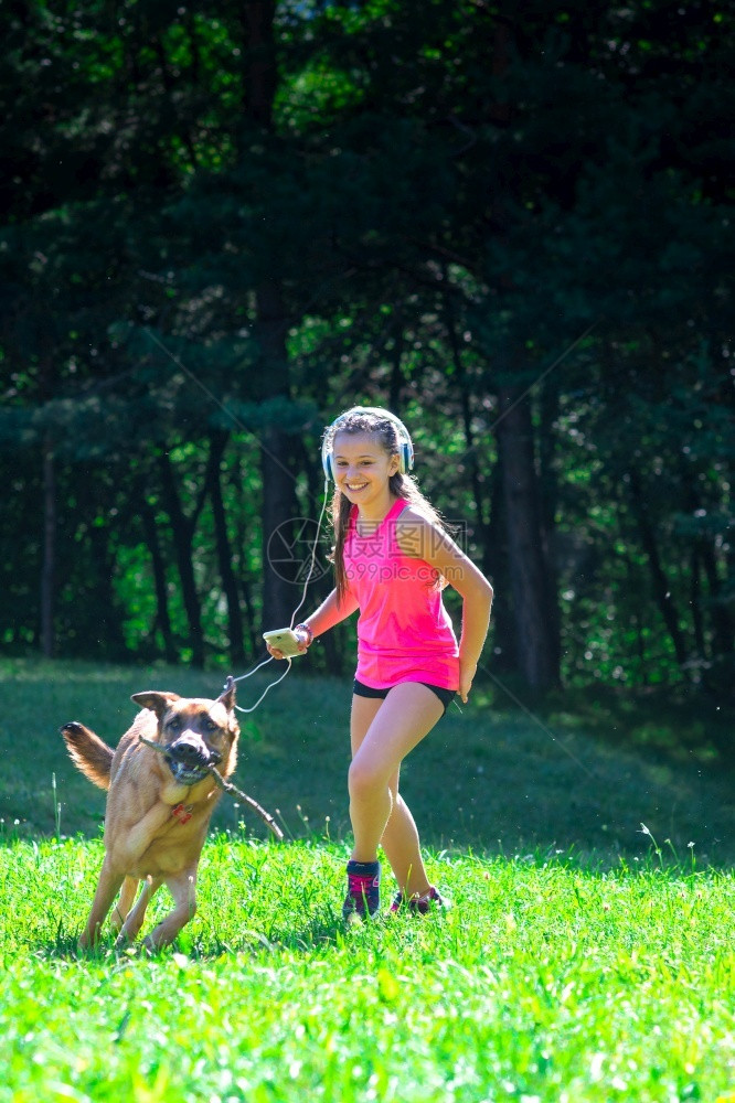 小女孩和她的德国牧羊犬在草地上玩狗愉快团结图片