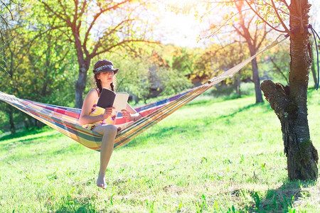 假期享受夏天在草地上坐吊床的女人会看书阅读图片