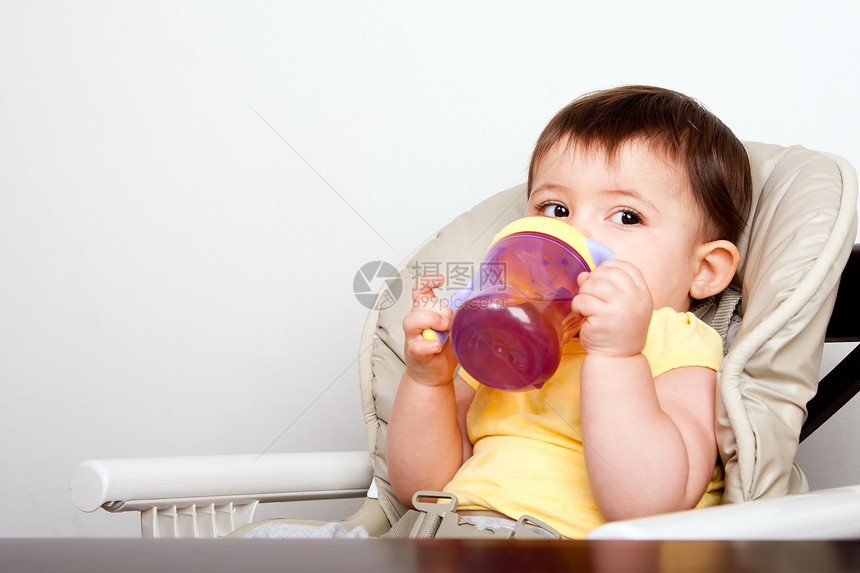 坐在椅子上喝吸水杯酒的婴儿女坐在椅子上水合物男杯子图片
