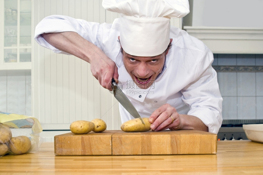 一个眼神疯狂的厨师凶猛地割土豆单身的轧制暂停图片