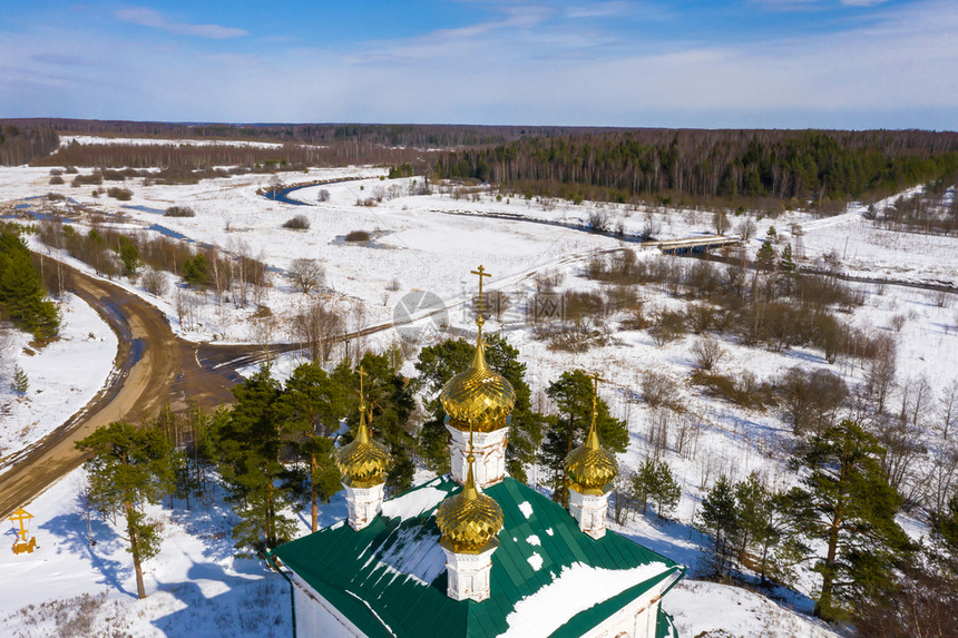 蓝色的伊凡诺沃地区Stromikhino村基督复活教堂金色圆顶在阳光明媚的一天以雪田和森林为背景云一种图片