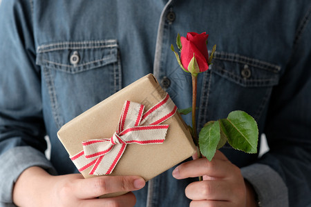 情人节男人手握红玫瑰和礼品盒图片
