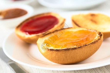 非洲大陆早餐包括加黄油桃子和草莓果酱的烤面包卷以自然光显示选择焦点在第一个面包卷大陆早餐中关注桃果酱前方第一张面包卷大陆早餐重点背景图片