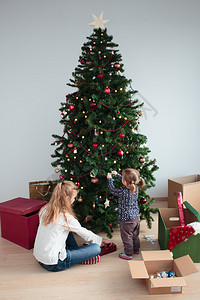 传统的年轻女孩和小妹在家里装饰圣诞树在家中装饰圣诞树庭学步的儿童图片