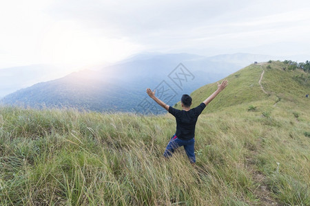 提高快乐的年轻人站在山上举起手来调色流浪癖图片