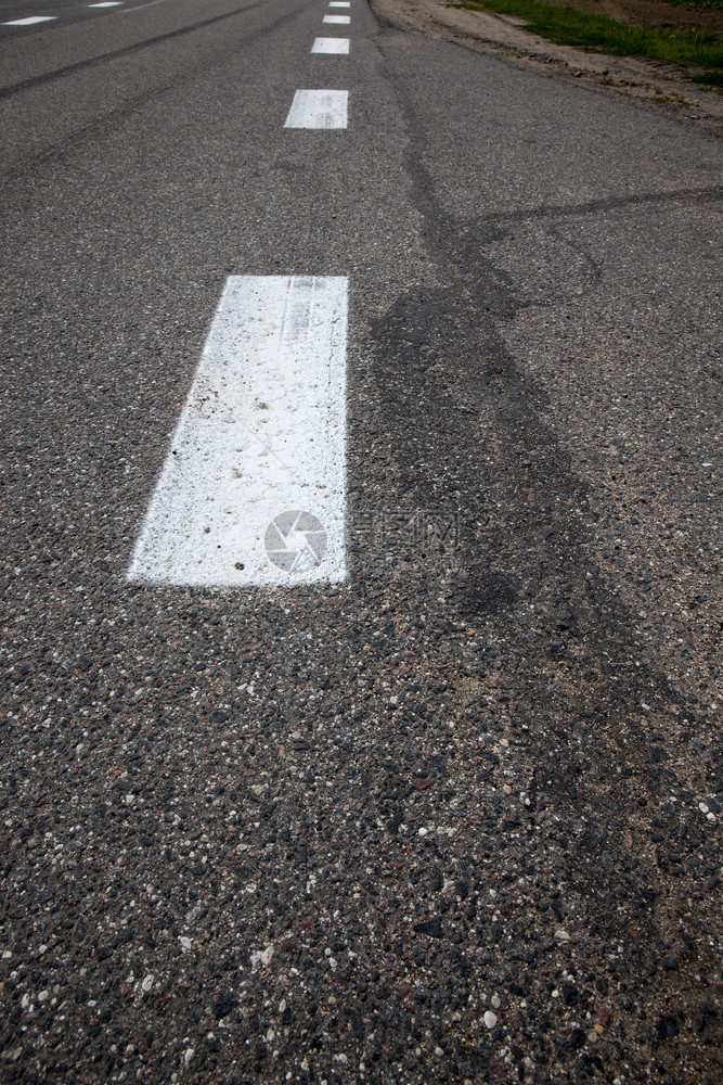 追踪明亮的黑色沥青路上的间断白色道路标志汽车图片