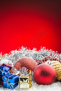 假期红色的底雪上圣诞饰品礼盒和球明亮的图片