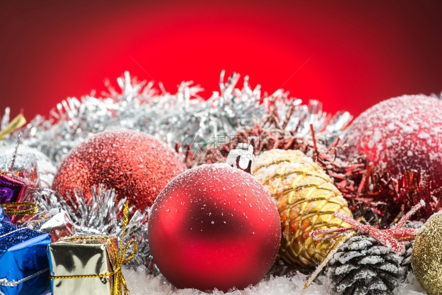 锥体红色的底雪上圣诞饰品礼盒和球子图片