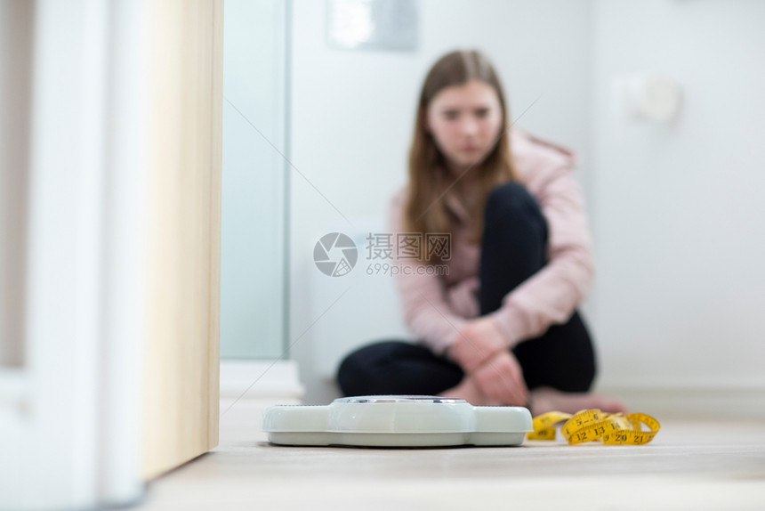 复制坐在浴室看天平和磁带测量仪的不快乐少女坐沮丧的着图片