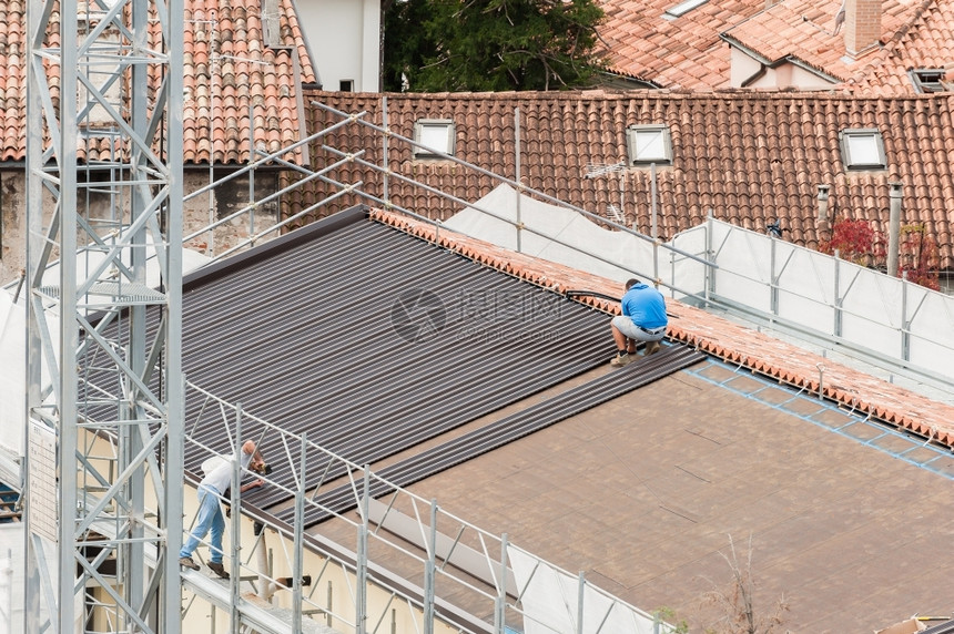 使固定建筑屋顶大楼翻修的工人建筑房顶改造中的工人男业的图片