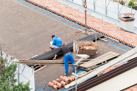 建筑屋顶大楼翻修的工人建筑房顶改造中的工人屋顶男艺图片