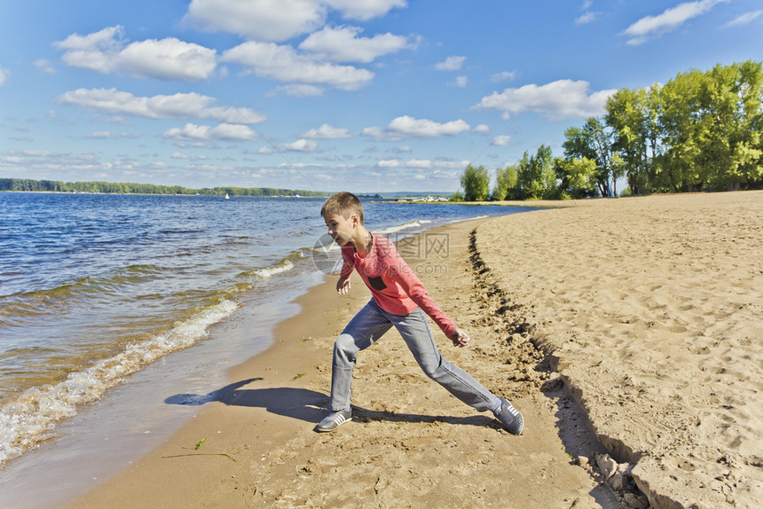 孩子穿粉红色衣服的男孩们在堤岸边的海滩上扔沙子腾一种图片