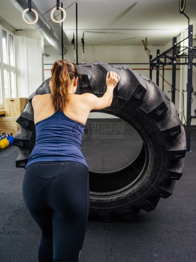 在后面重的一名年轻女子在健身房训练时使用拖拉机轮胎A的照片健美图片