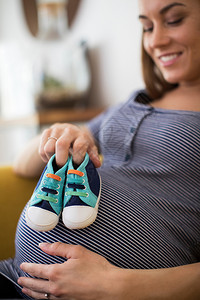 微笑在家养婴儿鞋时坐在索法的孕妇保持男生图片