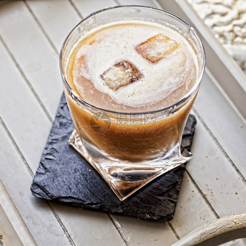 酒杯在黑石海岸上用两块冰方形平图象酒鬼黑色的威士忌酒图片