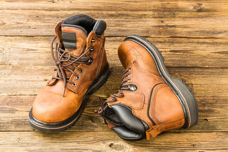 橡胶耐用的衬垫木制背景棕褐皮靴子图片