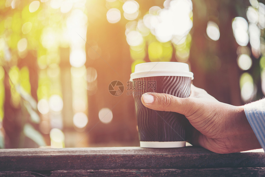 热的休息男人手持纸杯咖啡在自然清晨的背面男人手拿着纸杯咖啡在自然清晨的背景上带走图片