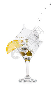 冰寒冷的液体鸡尾酒杯中以橄榄喷洒的马提尼水花将橄榄撒在鸡尾酒杯中图片