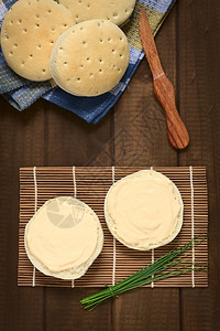 上面的奶油乳酪镜头散布在面包上侧边有一捆子用自然光拍照木制的起司图片