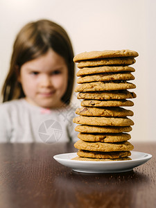 孩子盘脸一个年轻女孩看着一堆巧克力薯片饼干的照专注在曲奇饼上图片