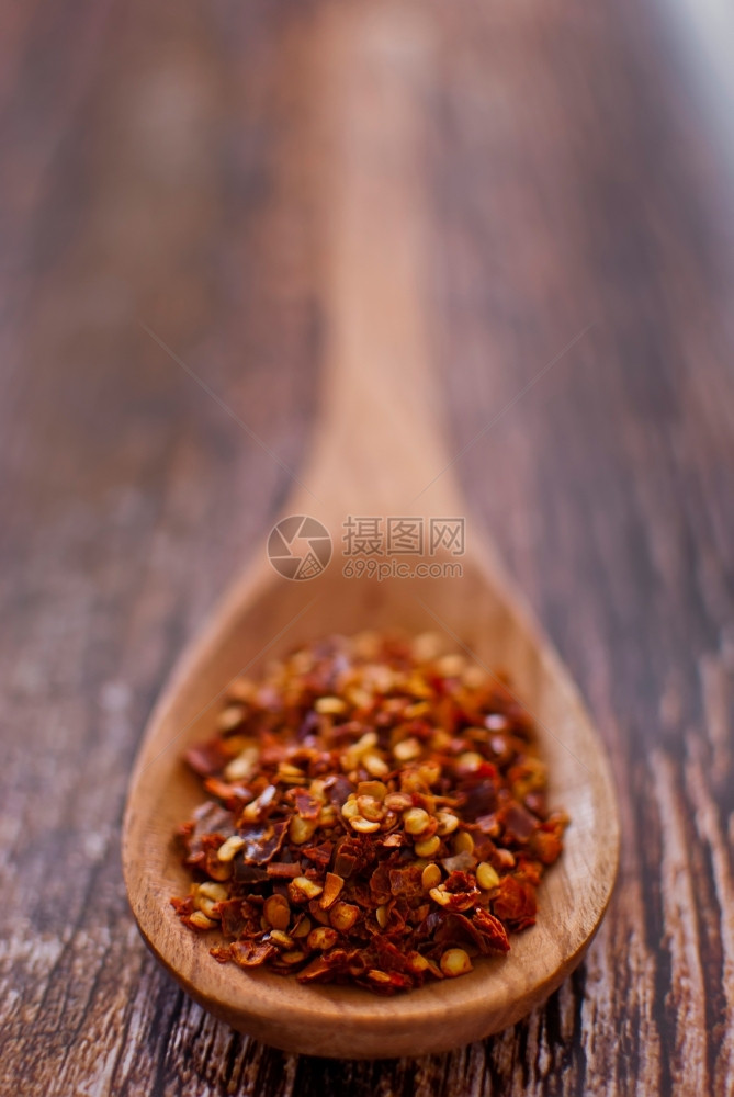 干燥有机的木勺制红辣椒片在木本背景之上有选择的重点寒冷图片