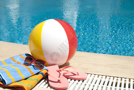游泳池旁的太阳镜毛巾拖鞋充气球图片