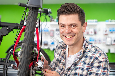 快乐的微笑人们自行车修理店男小企业主修理轮胎的肖像汽车修理厂图片