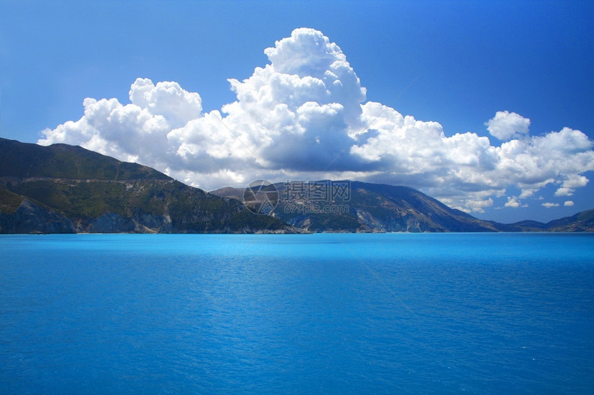 海滩太阳泻湖蓝天空和绿海景地平线上有山峰和白云图片