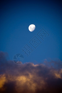 太阴几乎满的白月亮在乌云最后光芒下升起黑暗的天文学图片