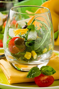 番茄绿色木制餐桌上杯子里混合沙拉的美味开胃菜盘子一种图片